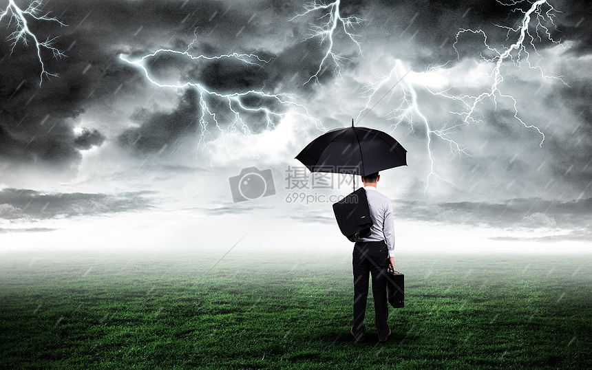 打伞商务人站在打雷下雨的草坪上图片