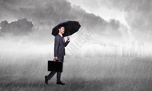 商人在暴风雨的天空下拿着一把伞背景图片