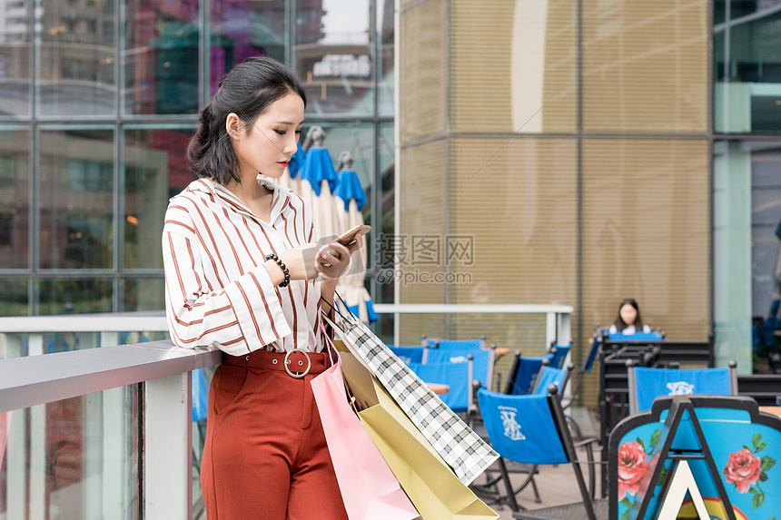 提着购物袋打电话逛街的美女图片