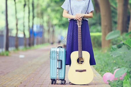 穿花裙子女孩小道上的吉他女孩行李箱背景