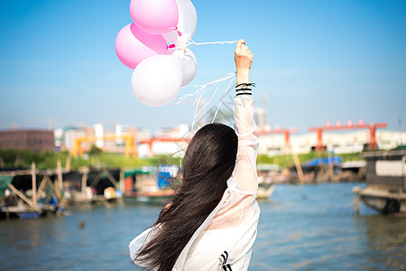 天空气球拿着气球的年轻女性背影背景