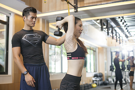 男教练在健身房给女性练习力量背景图片