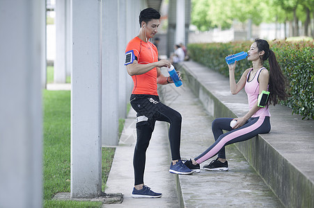 男女喝水年轻男女在户外锻炼后休息喝水背景