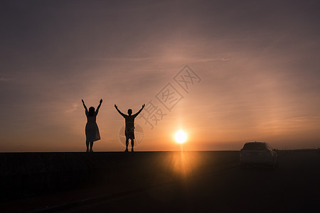 情侣在夕阳下拍摄剪影图片