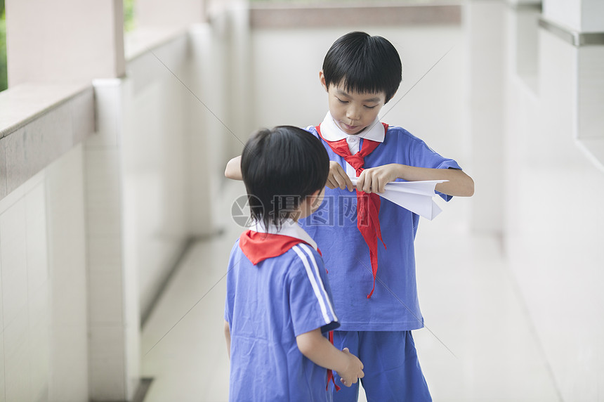 男学生在学校里折飞机玩耍图片