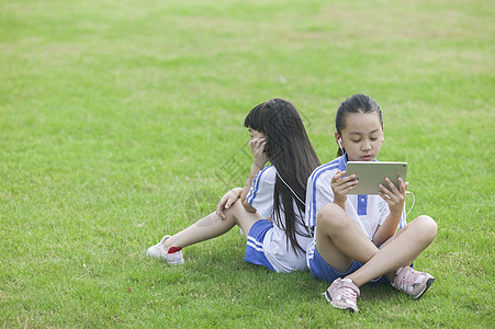 远程教育女同学在学校里草坪上用ipad 学习背景