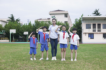 少先队员敬礼女老师和男女同学在操场上升国旗敬礼背景