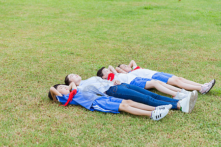 男孩和女孩学生们和老师躺在草地上背景