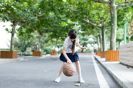 校园林荫道上打篮球的小学生女生高清图片