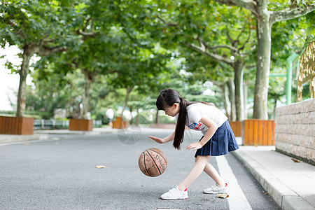 校园林荫道上打篮球的小学生女生高清图片