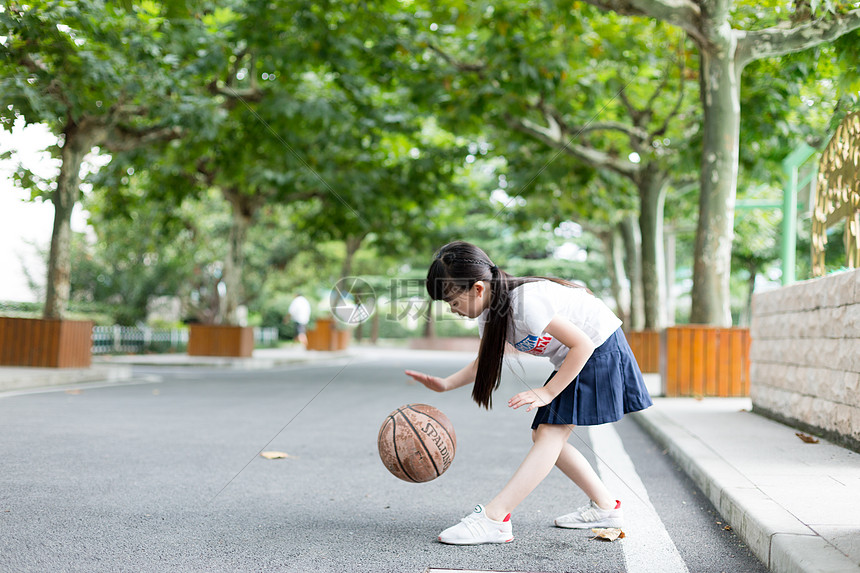 校园林荫道上打篮球的小学生女生