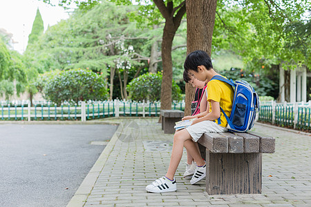 小学生背着书包坐在大树下背着书包的小学生背景