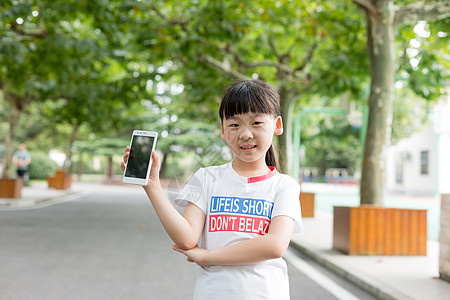 站在校园里玩手机的小学生女生高清图片