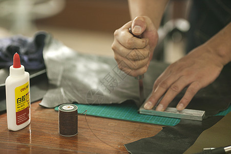 皮匠师傅专注的在裁切皮革背景图片