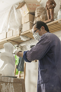 专注的石匠雕刻师傅在雕刻作品图片