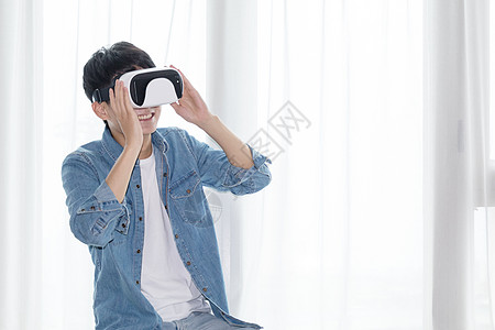 年轻男子在客厅体验虚拟现实VR眼镜图片
