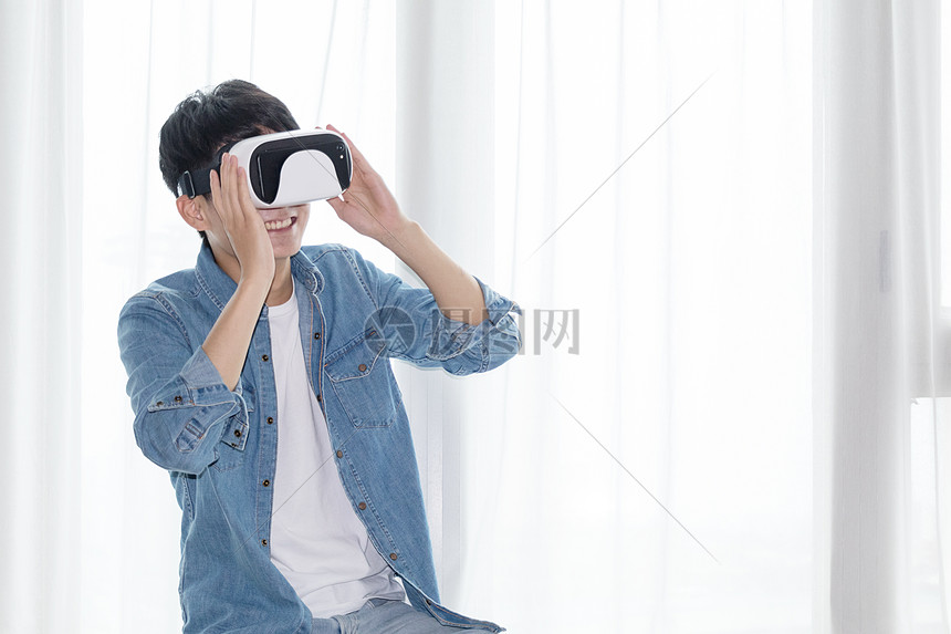 年轻男子在客厅体验虚拟现实VR眼镜图片