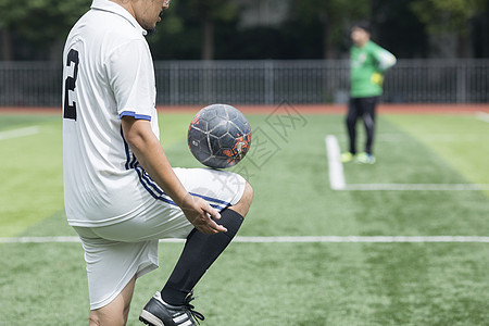 足球运动员在草坪上训练踢球背景图片