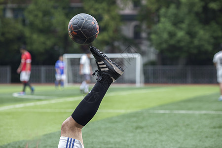 足球运动员在草坪上训练踢球背景图片