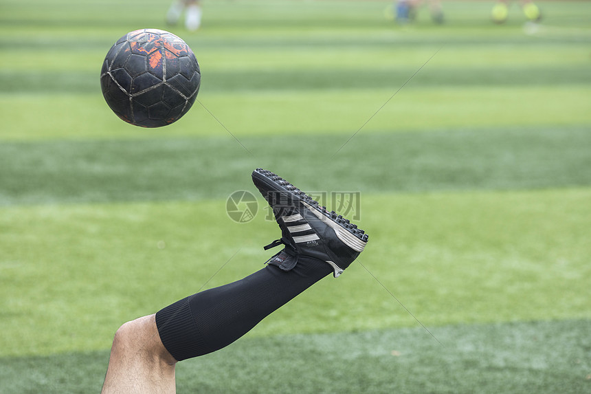 足球运动员在草坪上训练踢球图片