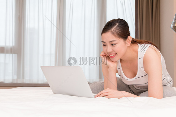 美女趴在床上玩电脑图片