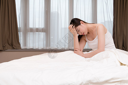 年轻女性失眠头痛坐在床上高清图片