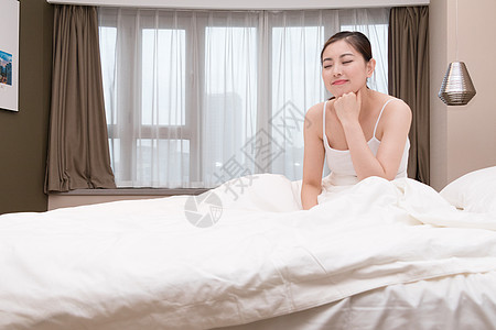 早上起床坐着伸展身体的年轻女性高清图片