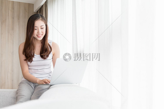 坐在客厅休闲放松玩电脑购物的女生图片