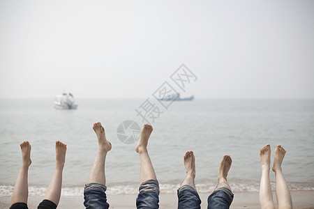 旅行中一家人在海边抬脚放松图片
