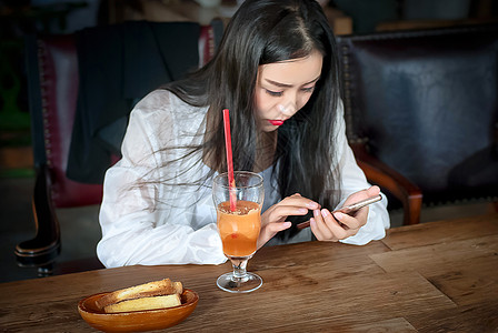 甜品和饮料咖啡厅玩手机的年轻女生背景