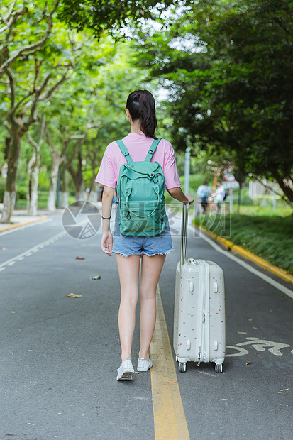 校园内女生拉旅行箱背影