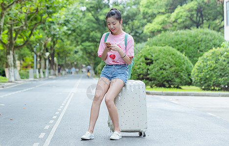 国庆手机海报校园女生坐旅行箱上看手机背景