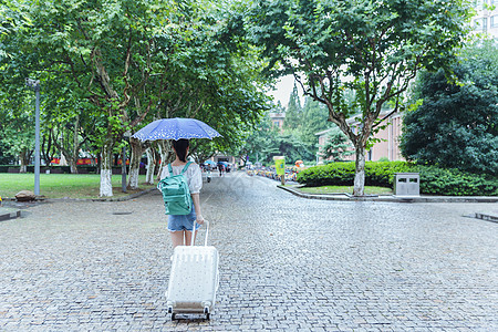 下雨天女生拉旅行箱背影高清图片