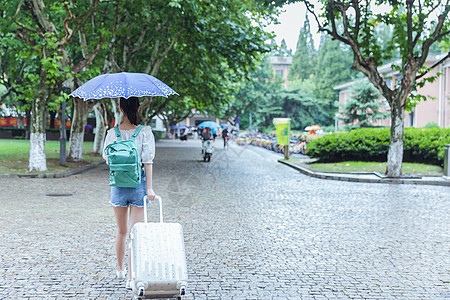 下雨天女生拉旅行箱背影高清图片