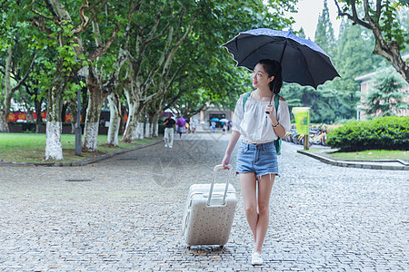 下雨天女生拉旅行箱张望高清图片