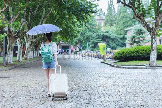 下雨天女生拉旅行箱背影