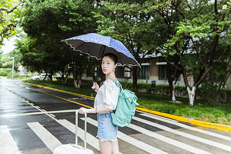 下雨天女生拉旅行箱回头高清图片