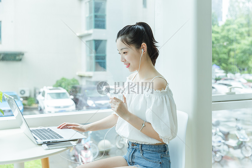 咖啡馆女生手拿水看电脑学习图片