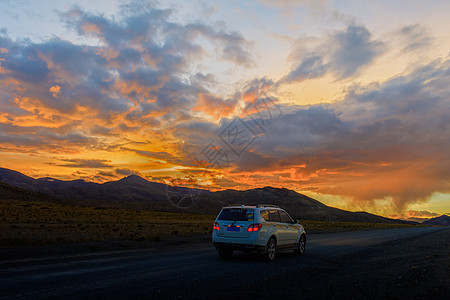 自驾旅行夕阳下行驶在公路上的汽车背景