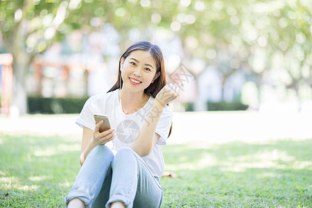 女大学生听音乐校园草坪上看手机听音乐的女生背景