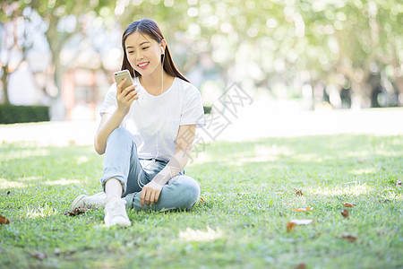 女大学生听音乐校园草坪上看手机听音乐的女生背景