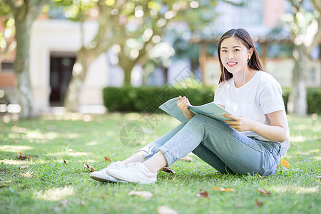 坐在校园草坪上看书的女学生背景