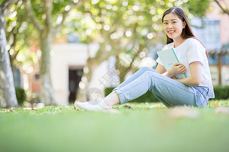 美女读书阳光坐在校园草坪上看书的女学生背景
