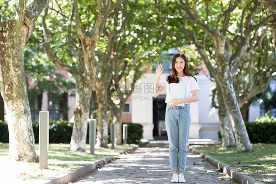 校园里拿着书微笑打招呼的女生图片