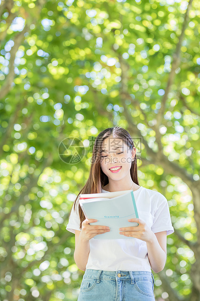 校园林荫道上微笑看书的学生图片