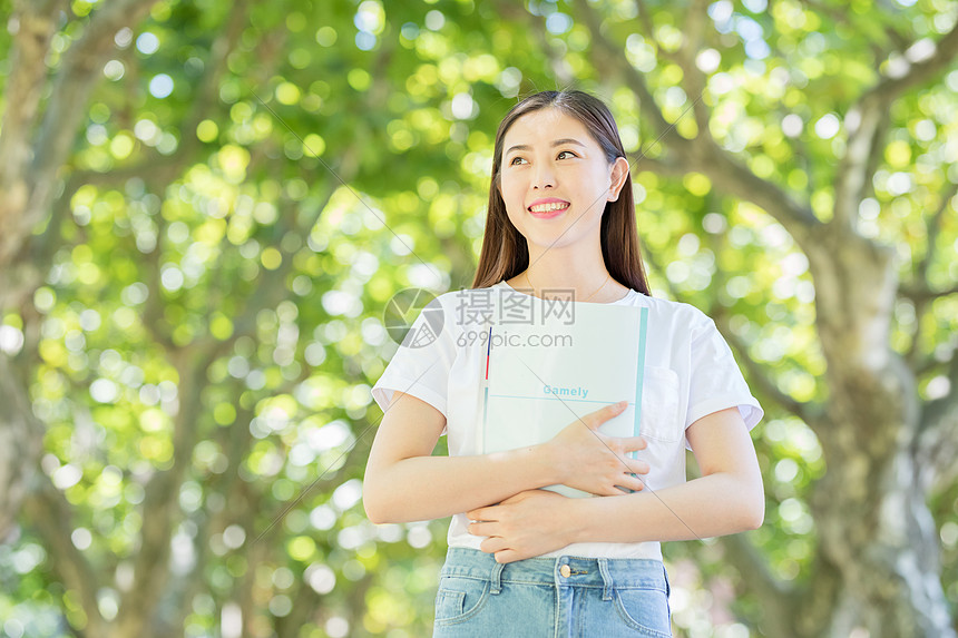 校园林荫道上微笑看书的学生图片