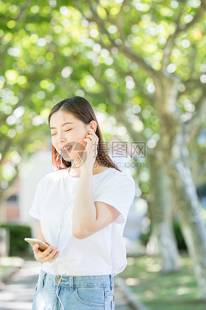 树下用手机听音乐的甜美女生图片