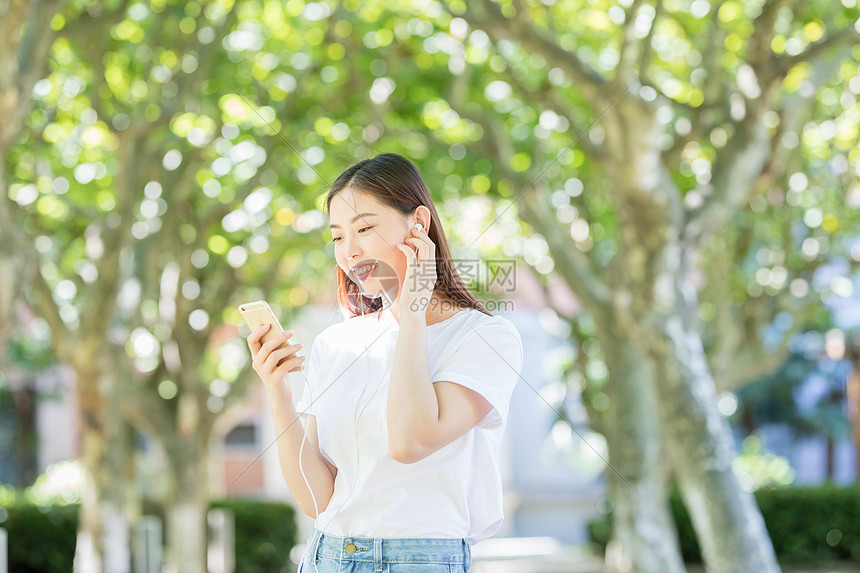 树下用手机听音乐的甜美女生图片