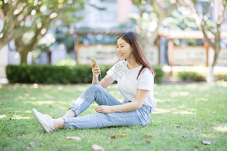 坐在校园草坪上玩手机的女生图片