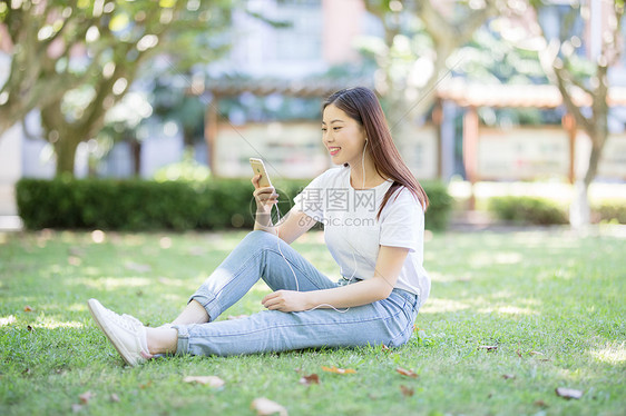 坐在校园草坪上玩手机的女生图片